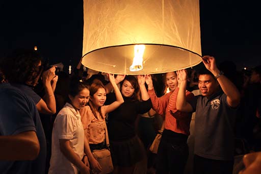 A family lighting a lantern together during the Chiang Mai lantern festival